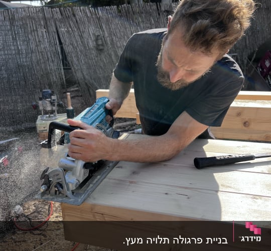 אדם חותך עץ עם מסור חשמלי בגינה